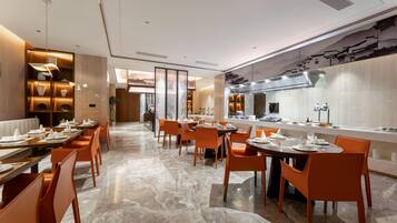 Un restaurante moderno con una barra larga, sillas color naranja y piso de mármol.