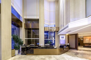 Un hall espacioso con mostrador de recepción, ventanas amplias y un techo alto.