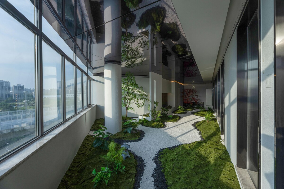 A modern interior with a glass corridor, indoor plants, and a view of the city.