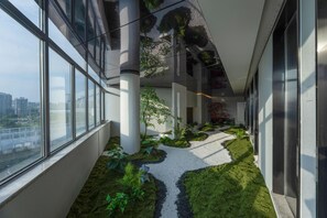 A modern interior with a glass corridor, indoor plants, and a view of the city. - Madison Hotel Hefei 2nd Affiliated Hospital (Hefei)