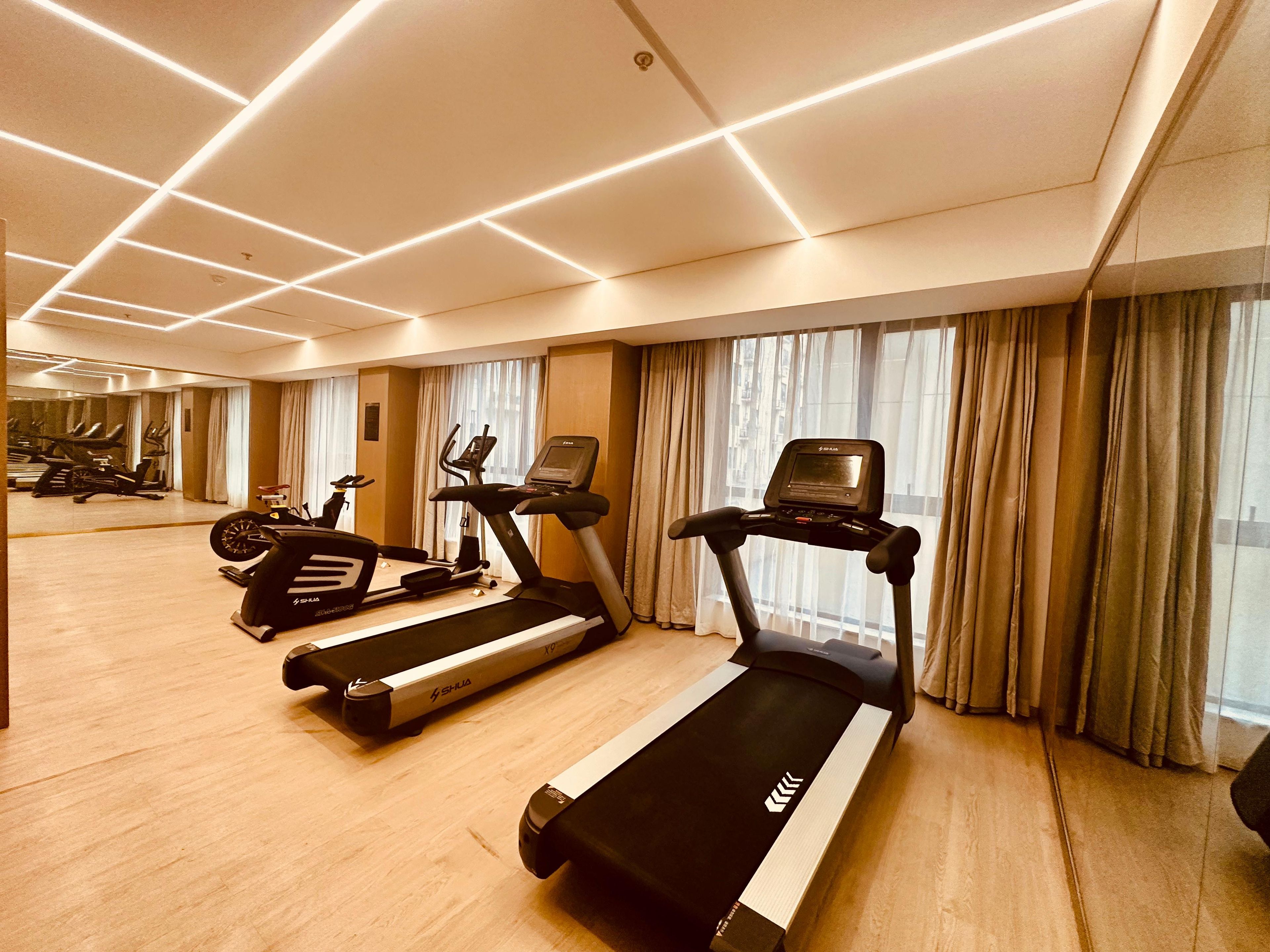 Un gimnasio moderno con cintas de correr, bicicletas estáticas y elípticas.