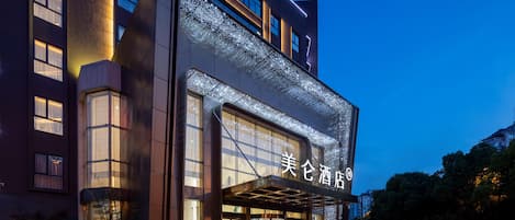 A modern hotel entrance with a glass facade and illuminated signage.
