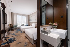 A hotel room with two beds, a desk, a chair, a large window with curtains, a bathroom with a mirror, sink, and towel rack. - Madison Hotel Hefei 2nd Affiliated Hospital (Hefei)