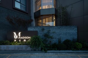 A building with a prominent 'M' sign and Chinese characters, surrounded by greenery. - Madison Hotel Hefei 2nd Affiliated Hospital (Hefei)