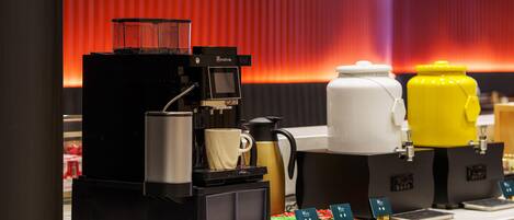 Una estación de café con una máquina de café, espumador de leche y dispensador de agua.