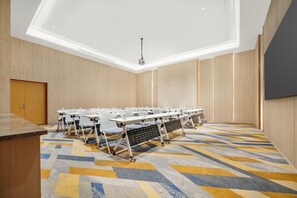Ein Konferenzraum mit einem langen Tisch, Stühlen und einer Projektionsleinwand.