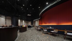 Un vestíbulo moderno con una pared roja curva, un mostrador de recepción y zonas de estar.