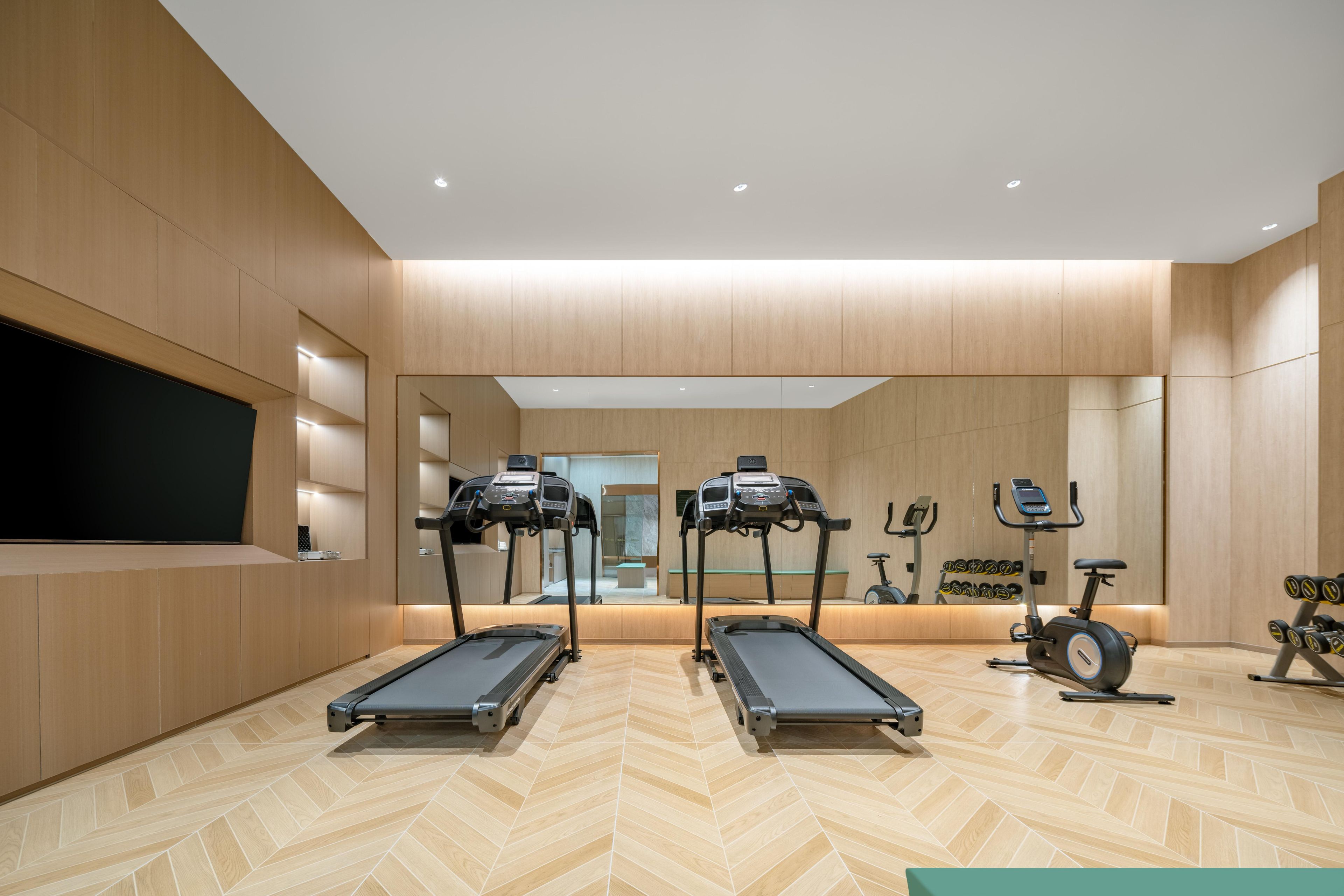 Un gimnasio moderno con dos cintas de correr, una elíptica y una bicicleta estática.