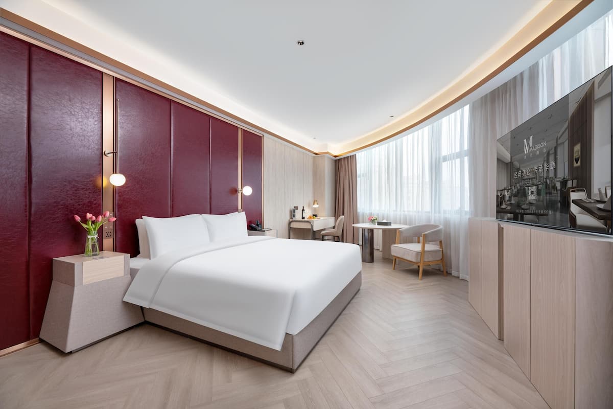 Una habitación de hotel moderna con una cama grande, un escritorio y un área de descanso.