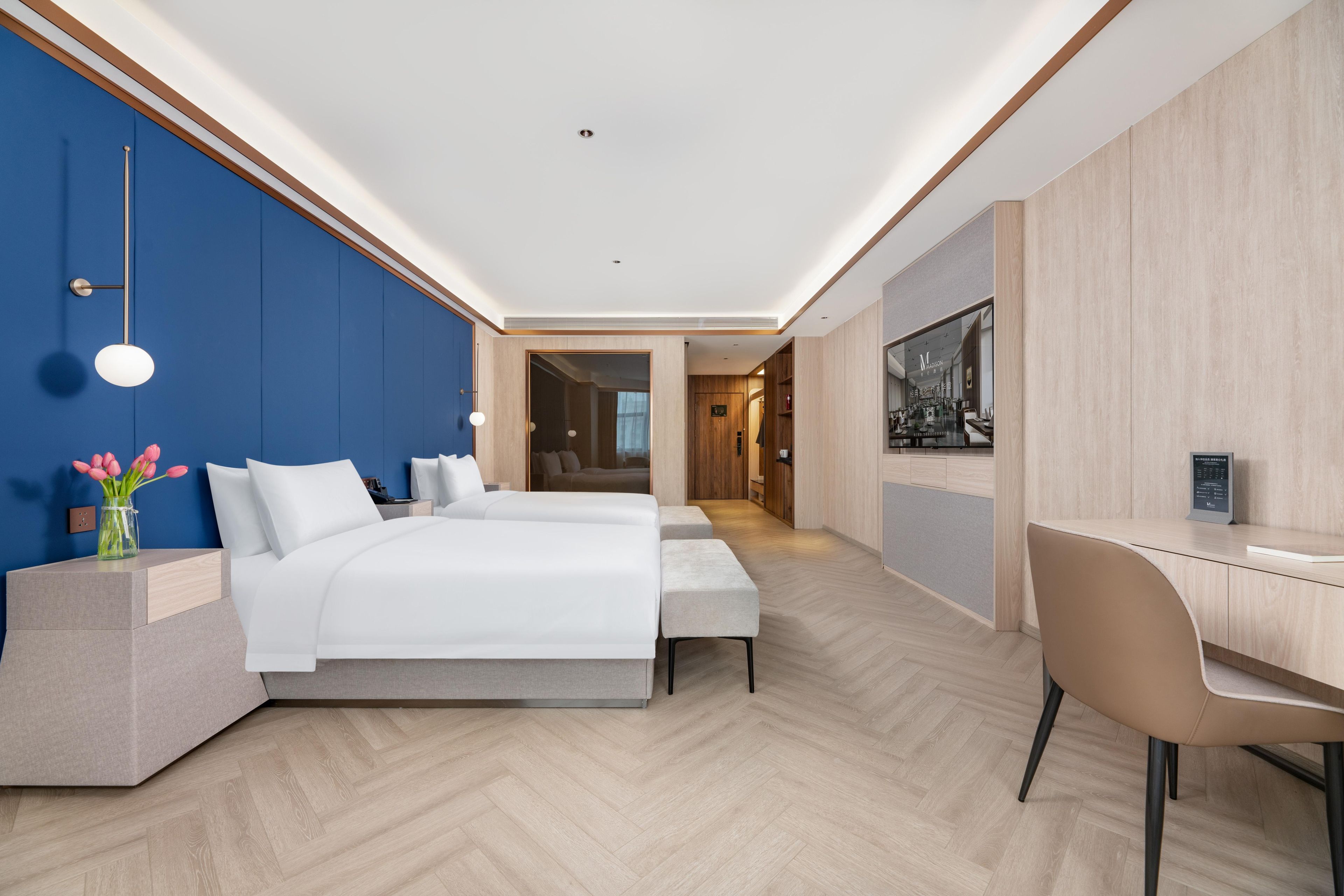 Habitación de hotel moderna con una cama grande, un escritorio y vistas al pasillo.