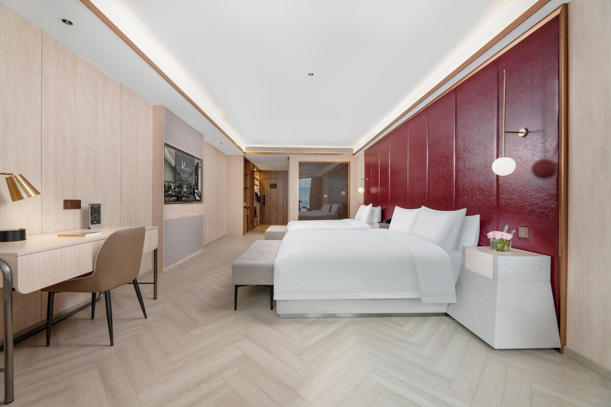 Une chambre d’hôtel moderne, dotée d’un grand lit, d’un bureau et d’une chaise.