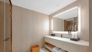 Un baño moderno con un espejo grande, tocador de madera y una pequeña cesta de mimbre.