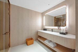 Un baño moderno con un espejo grande, tocador de madera y una pequeña cesta de mimbre.