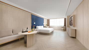 Ein modernes Hotelzimmer mit einer Couch, einem Bett, einem Esstisch und einem Einbauschrank.
