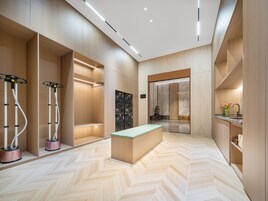 Una habitación de hotel moderna con suelo de diseño en patrón espiga, un banco central y dos sillones de masaje.