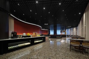 Un moderno hall de hotel con piso de granito pulido, un mostrador de recepción central y zonas de estar.