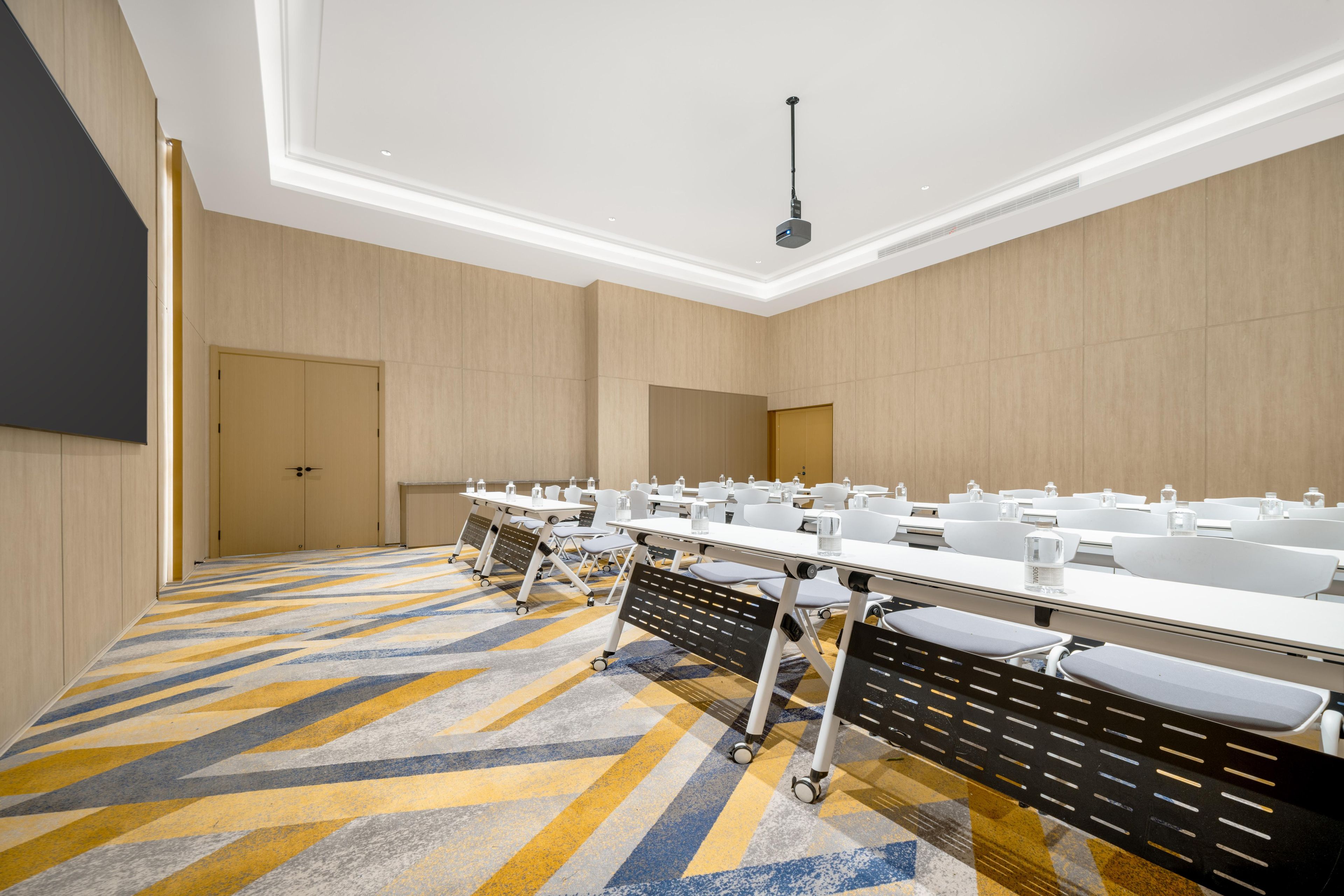 Un salón de conferencias con una larga mesa, sillas y un proyector.