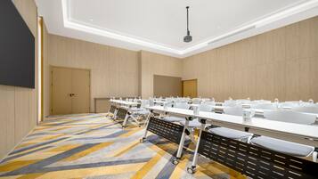 Un salón de conferencias con una larga mesa, sillas y un proyector.