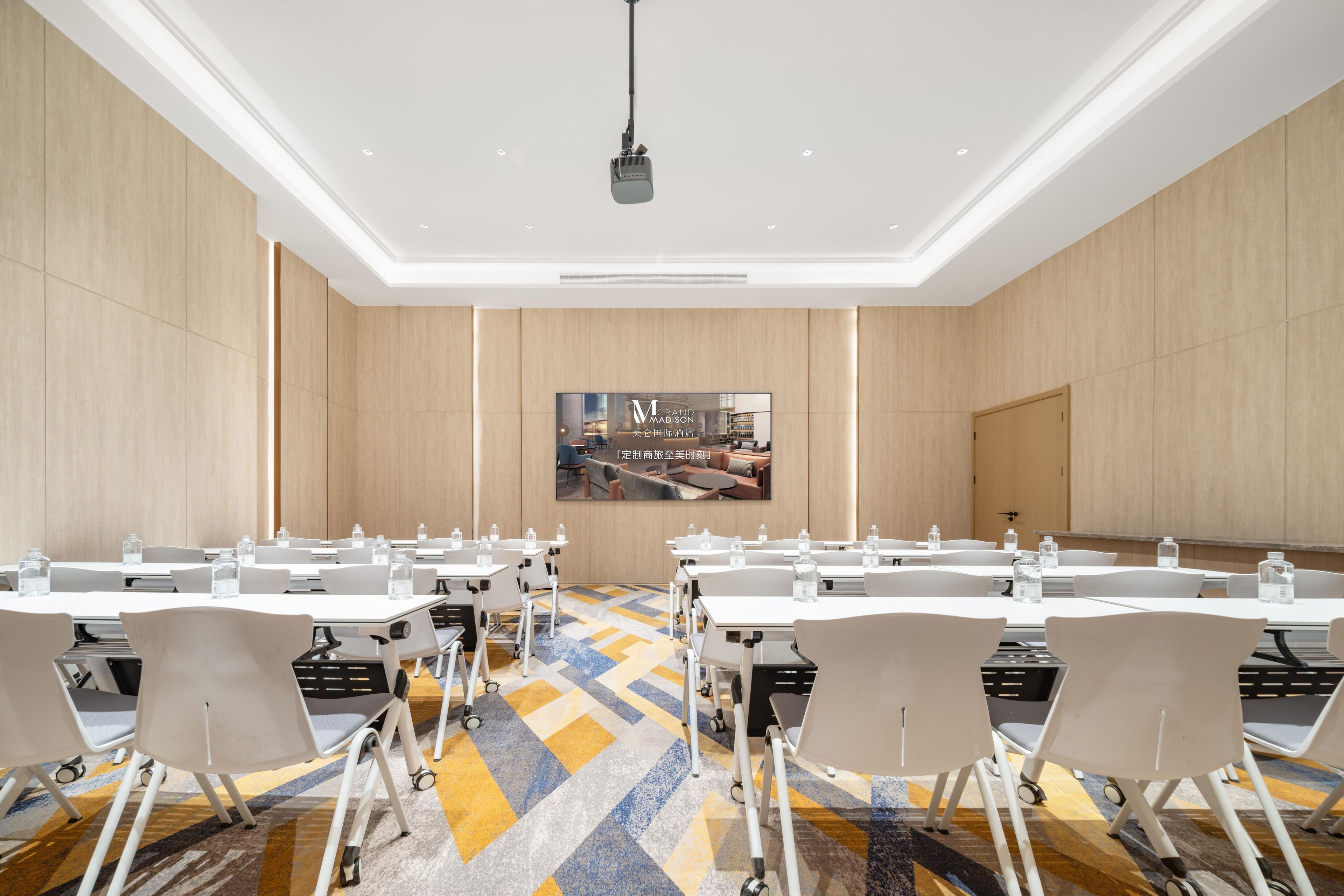 Un salón de conferencias con mesas, sillas y un proyector.