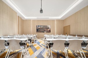 A conference room with tables, chairs, and a projector.
