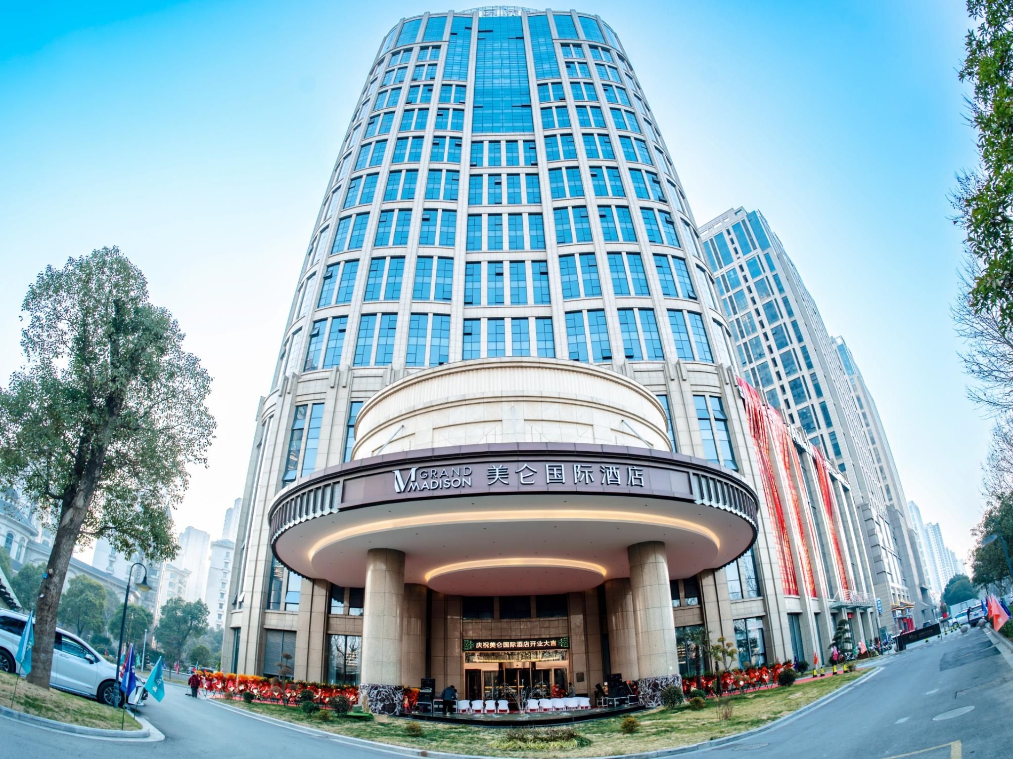 Un hotel moderno con entrada circular, varios pisos y una fachada de vidrio destacada.