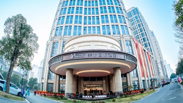 Un hotel moderno con entrada circular, varios pisos y una fachada de vidrio destacada.