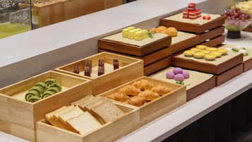A buffet with various food items including pastries, sandwiches, and desserts.