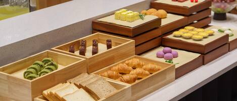 Un bufé con diversos alimentos, incluyendo pasteles, sándwiches y postres.