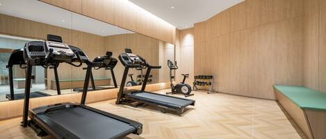 A modern gym with treadmills, stationary bikes, and a mirrored wall.