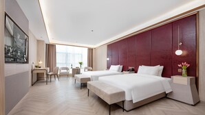 Una habitación de hotel moderna con dos camas, un escritorio, una silla y un ventanal grande.