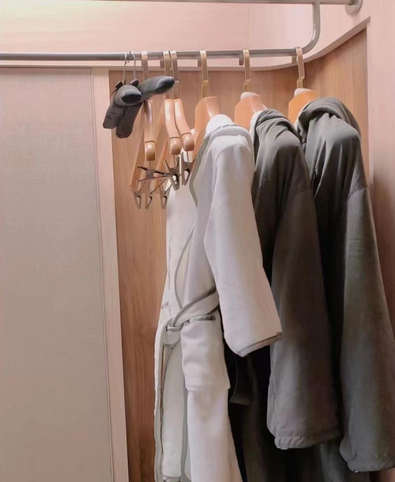 A closet with wooden doors and a metal rod for hanging clothes.