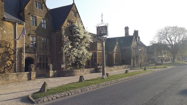 A traditional stone building with a flagpole, a street lamp, and a clear road.
