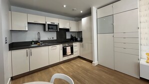 A modern kitchen with white cabinets, a microwave, and a sink. - 1-Bed Apt, Sleeps 4, Central To Shops & Transport (London)