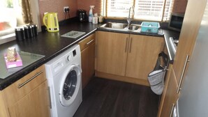 A compact kitchen with a washing machine, a sink, and a kettle. - Two bedroom timber lodge,  Avonvale Holiday Lodges (Evesham)