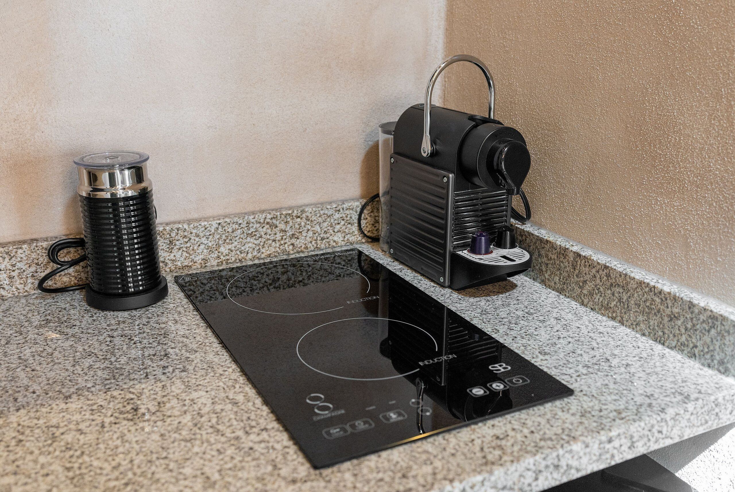 A kitchen with an induction cooktop, a kettle, and a coffee maker.