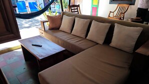 Une pièce avec un canapé beige, une table basse en bois et un hamac.