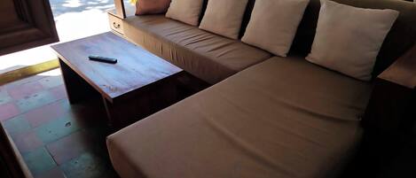 Una habitación con un sofá color beige, una mesa de centro de madera y una hamaca.