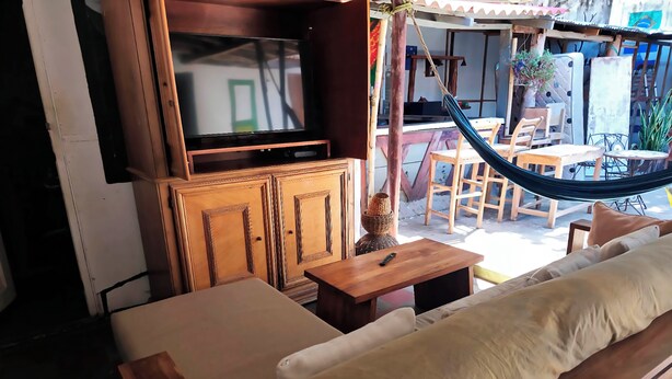 Un espace de détente extérieur accueillant, avec un canapé en bois, une petite table et un hamac.