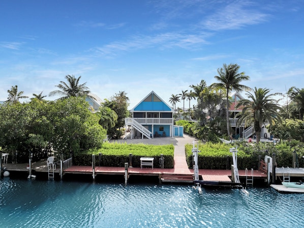 Surrounded by lush greenery, this resort features a balcony, staircase, and a dock extending into a pool.