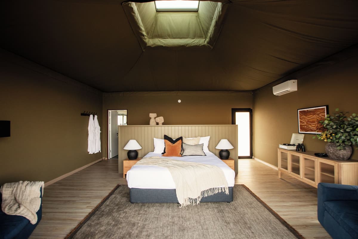 A spacious bedroom with a large bed, bedside lamps, a small cabinet, and a ceiling skylight.