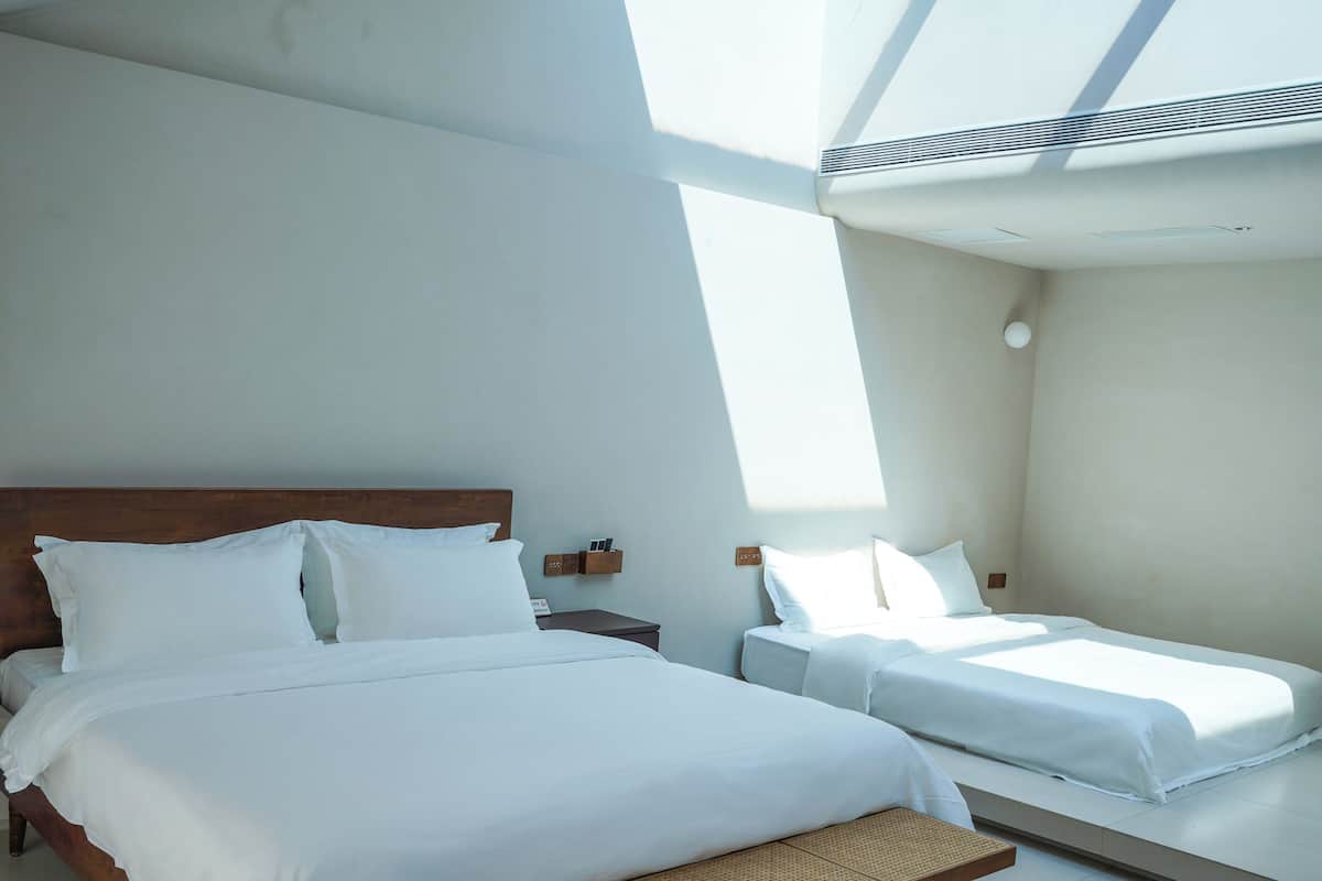 A hotel room with a large bed, a smaller bed, a bench, and a skylight.
