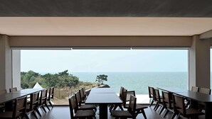 A dining area with a large table and chairs, overlooking a scenic view of the sea and greenery. - Huyu Homestay (Suzhou)