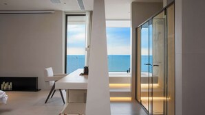 A modern interior with a large window overlooking the sea, a minimalist dining area, and a glass-enclosed shower area. - Huyu Homestay (Suzhou)
