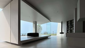 A modern interior with large windows, a black bench, and a bookshelf. - Huyu Homestay (Suzhou)