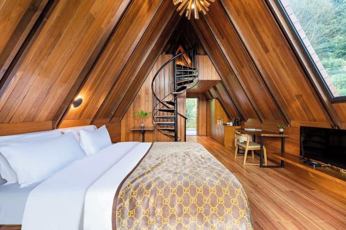 A cozy, wood-paneled bedroom with a bed, a desk, and a TV.