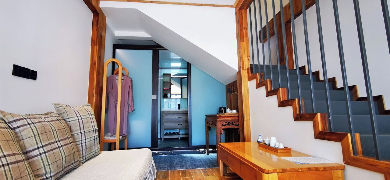 Una habitación con una cama, una mesa de madera, una escalera y un armario.