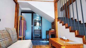 Una habitación con una cama, una mesa de madera, una escalera y un armario.