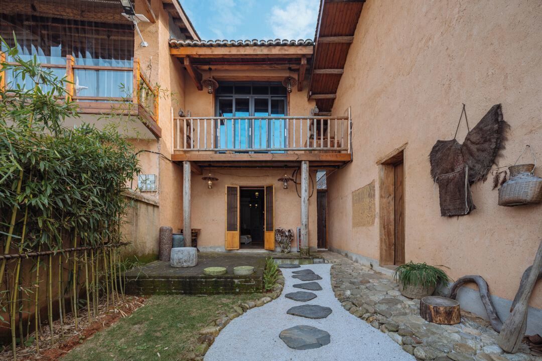 Un edificio tradicional con balcón, sendero de piedra y decoración rústica.