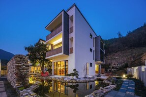 A modern two-story building with a stone wall and a reflective water feature in front. - Yichun Old Yu Xinzhi Homestay (Yichun)