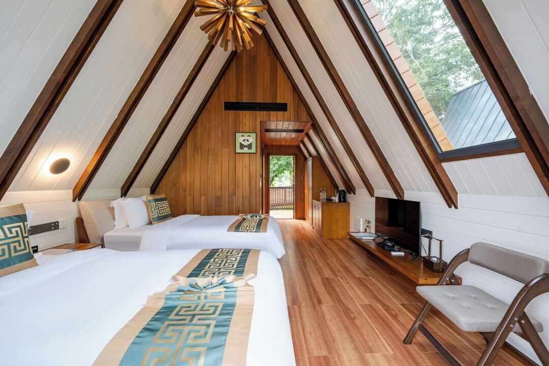 Acogedor dormitorio en el ático con dos camas, televisión y techo de madera.